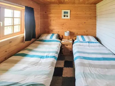 two beds in a log cabin with a desk at Forest Lodge in Dumfries