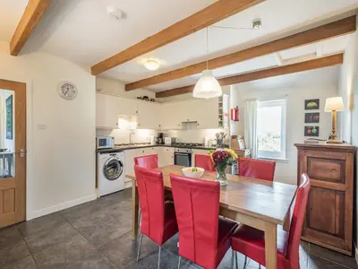 a kitchen with a wooden table and red chairs at Strathmaddie Farm Cottage in Palnure