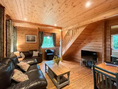 a living room with a leather couch and a fireplace at Criffel Lodge in Ringford