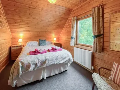 a bedroom with a bed with pink towels on it at Criffel Lodge in Ringford