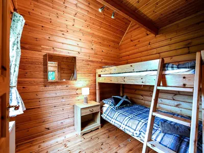 a bedroom with two bunk beds in a log cabin at Criffel Lodge in Ringford