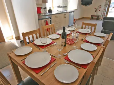 a wooden table with plates and wine glasses on it at Cairndoon Steading Whithorn in Carleton