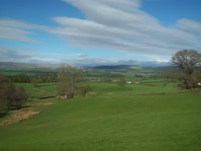 a green field with trees and mountains in the distance at Beuchan Cottage Keir Mill in Closeburn