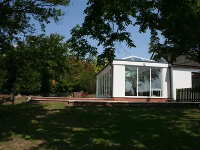 a house with a conservatory on a lawn at Dornock Brow Cottage in Dornock