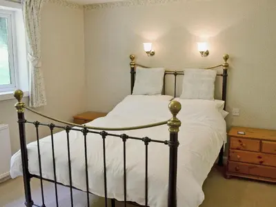 a bedroom with a large bed with white sheets and pillows at Squirrel Cottage in Palnure