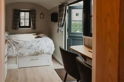 a small bedroom with a bed and a desk and a desk at Herdie Hideaway - Shepherds Hut in Wigton