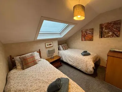 a attic bedroom with two beds and a skylight at Large country house with garden, outdoor spa area & games room with Hot Tub and Fire Pit in Wigtown