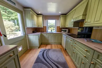a large kitchen with yellow cabinets and a window at Large country house with garden, outdoor spa area & games room with Hot Tub and Fire Pit in Wigtown