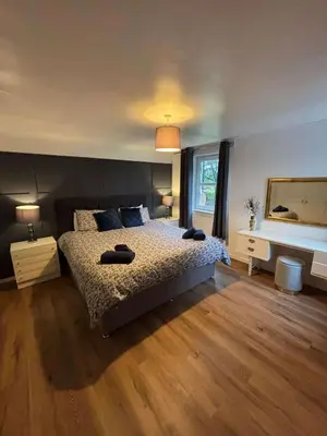 a bedroom with a large bed and a mirror at Large country house with garden, outdoor spa area & games room with Hot Tub and Fire Pit in Wigtown