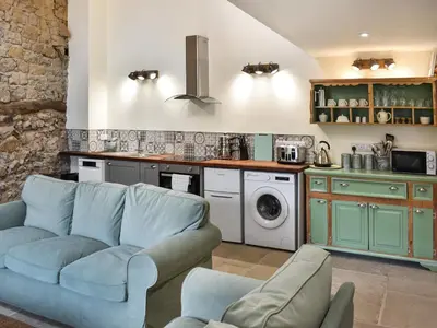 a living room with a blue couch and a kitchen at Pickles Barn in Ireby