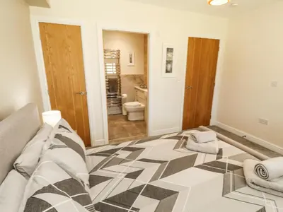 a bedroom with a bed and a bathroom at Squirrel Cottage in Penrith