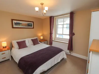 a bedroom with a large bed and a window at Lillibet Cottage in Keswick