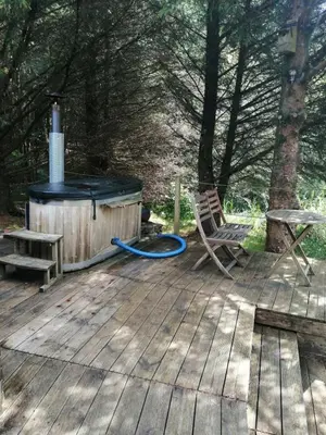 a wooden deck with a woodburning stove and a bench at Otter - Eco Bothy with Hot Tub in Castle Douglas