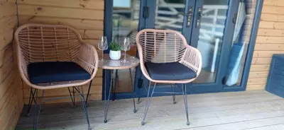 two chairs and a table on a porch at little peru luxury pods and alpaca farm in Crosshill