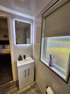 a bathroom with a white sink and a window at Top Lodge in Newton Stewart