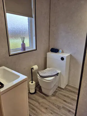 a bathroom with a toilet and a sink and a window at Top Lodge in Newton Stewart
