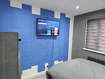 a bedroom with a blue tiled wall with a television at Bridgepay Modern 4 bedroom House in Cumbria - Whitehaven - Free Parking in Whitehaven