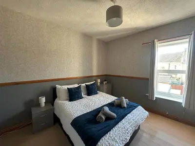 a bedroom with a bed with blue pillows and a window at Bolton Terrace - 2 Bedrooms - Sleeps 4 in Workington