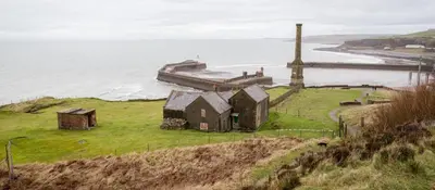 an old house on a hill next to the ocean at Harbour View - 1 Bedroom - Sleeps 2 in Whitehaven