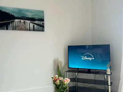a flat screen tv sitting on a stand next to a wall at Sea View Apartment - 2 Bedrooms - Sleeps 4 in Whitehaven