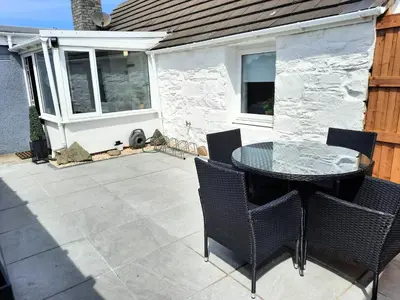 a patio with a glass table and chairs at Tigh Samhradh in Monreith