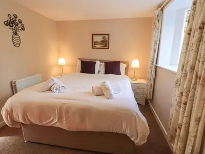 a bedroom with a large white bed with two pillows at Hollens Cottage in Ambleside