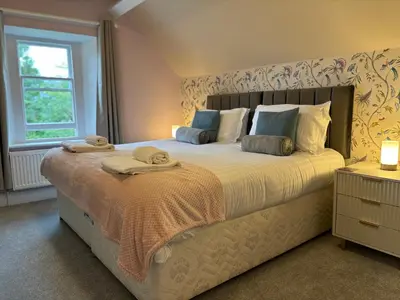 a bedroom with a large bed with towels on it at Fell215 - Classic loft apartment at The Lairbeck in Keswick in Keswick