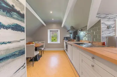 a kitchen with a sink and a dining table at Fell215 - Classic loft apartment at The Lairbeck in Keswick in Keswick