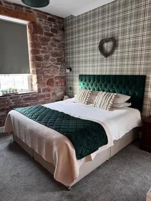a bedroom with a large bed with a green headboard at Ecclefechan Hotel in Ecclefechan