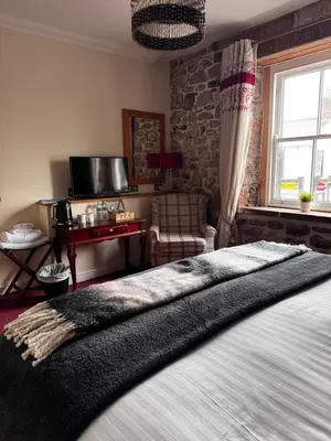 a bedroom with a bed and a chair and a window at Ecclefechan Hotel in Ecclefechan