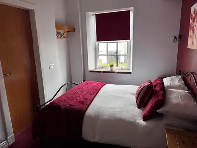 a bedroom with a bed with a red blanket and a window at Ecclefechan Hotel in Ecclefechan