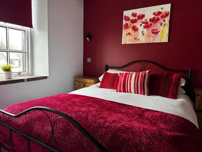 a red bedroom with a bed with red sheets and red pillows at Ecclefechan Hotel in Ecclefechan