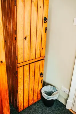 a wooden cabinet in a room with a trash can at Denton House Hostel in Keswick