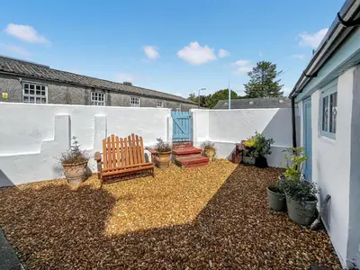 a patio with two chairs and potted plants at Bruce Cottage in Whithorn