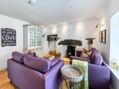 a living room with purple couches and a fireplace at Bruce Cottage in Whithorn