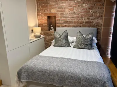 a bedroom with a white bed with a brick wall at Blencathra Barn in Penrith