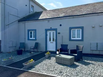 a blue house with blue chairs and a patio at North Lodge Retreat Allonby in Maryport