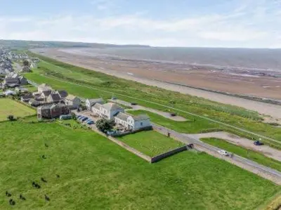 an aerial view of a house on a field next to the ocean at North Lodge Retreat Allonby in Maryport