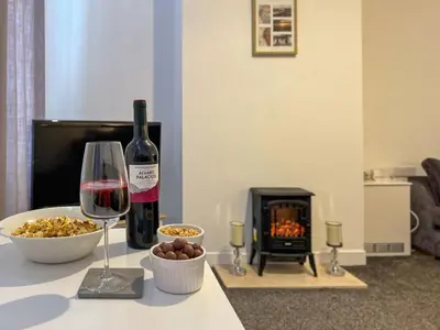 a bottle of wine and a bowl of food and a wine glass at North Lodge Retreat Allonby in Maryport