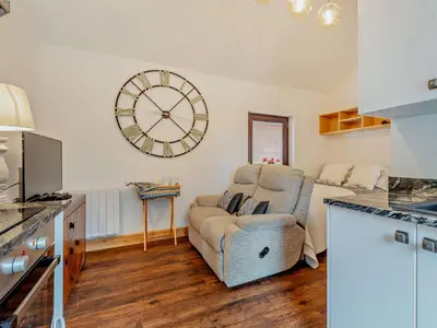 a living room with a chair and a clock on the wall at 1 Bed in Allonby 95499 in Allonby