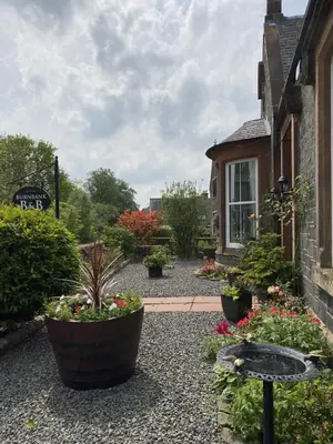 a garden with potted plants in front of a house at Burnbank Bed and Breakfast in Moffat