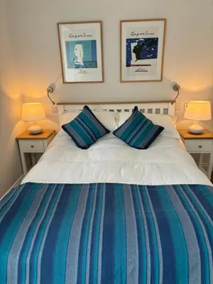 a bedroom with a bed with blue and white stripes at Stable Cottage in Lockerbie