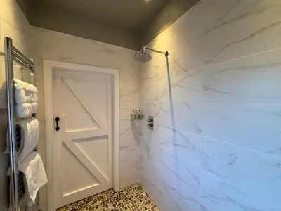 a bathroom with white marble walls and a door at Stable Cottage in Lockerbie
