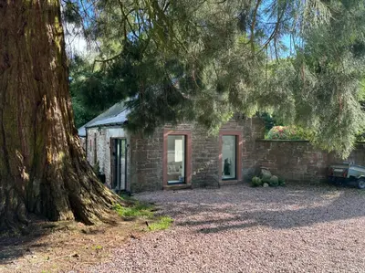a stone house with a tree in front of it at Stable Cottage in Lockerbie