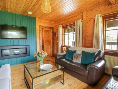 a living room with a leather couch and a tv at Glenisle in Dalbeattie