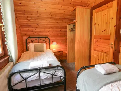 a bedroom with two beds in a log cabin at Glenisle in Dalbeattie