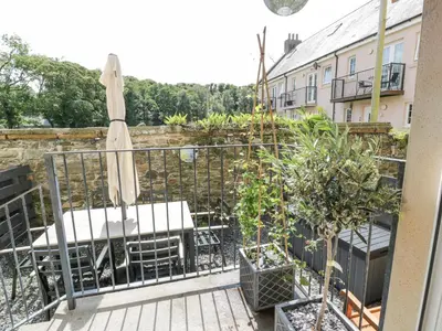 a balcony with an umbrella and a table and chairs at Ptarmigan in Newton Stewart
