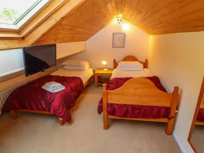 a attic room with two beds and a flat screen tv at Bluebells in Ambleside