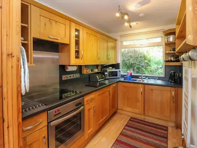a kitchen with wooden cabinets and stainless steel appliances at Bluebells in Ambleside