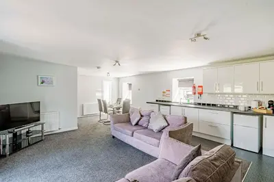 a living room with a couch and a kitchen at Auchenlarie Courtyard No 1 in Gatehouse of Fleet